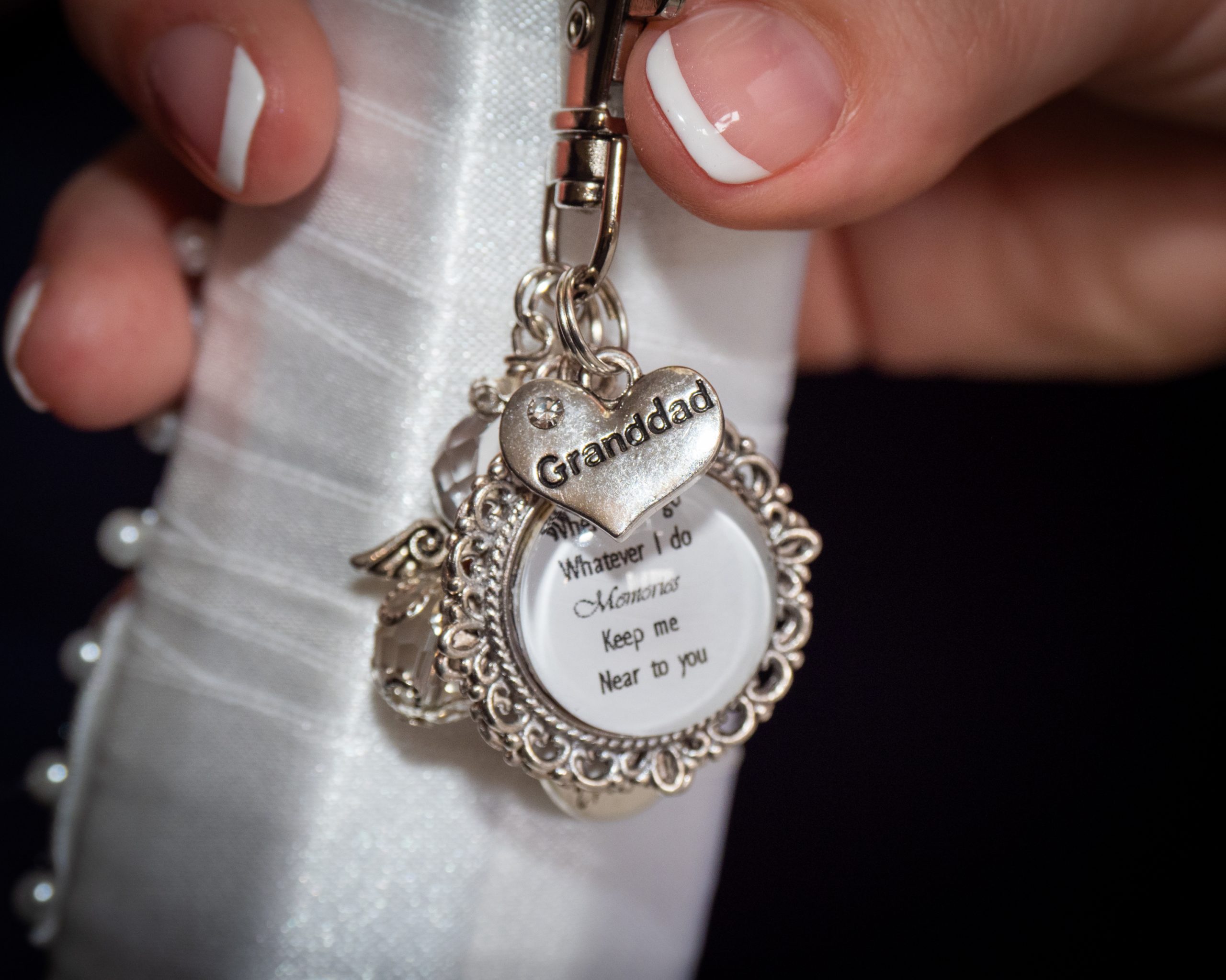 Close-up of bride's hand as she holds a little silver keyring remembering Grandad.